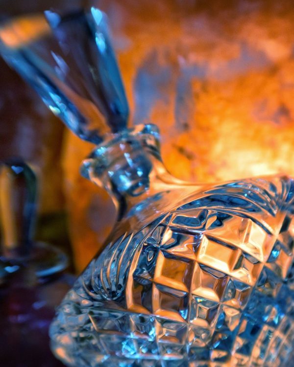 زجاجة عطر كريستالية يلمع فيها ضوء دافئ