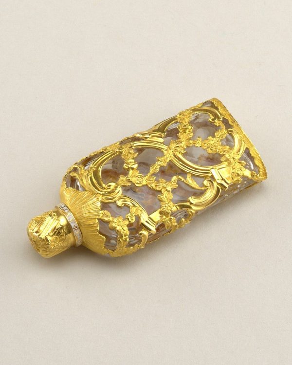 قارورة عطر صغيرة مغلّفة بزخارف ذهبية مخرّمة